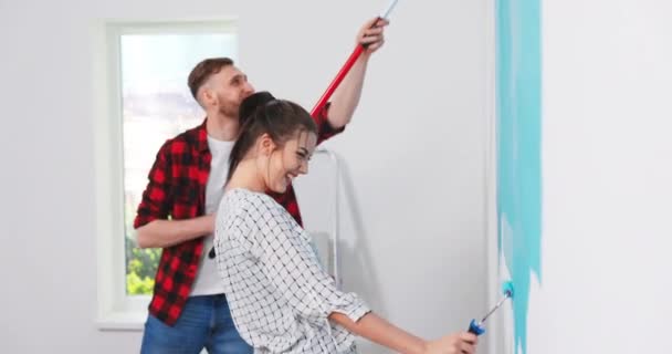 Bonito e bonito jovem caucasiano mulher pintura paredes no apartamento na cor azul com — Vídeo de Stock