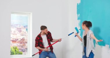 Genç çift dairelerini yenilerken eğleniyor. İnşaat, dekorasyon, boya fırçası. Ev dekorasyonu ve yenileme 