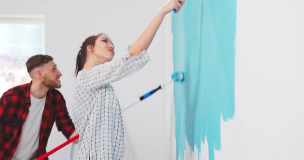 Linda y hermosa mujer caucásica joven pintando paredes en el apartamento en color azul con — Vídeos de Stock