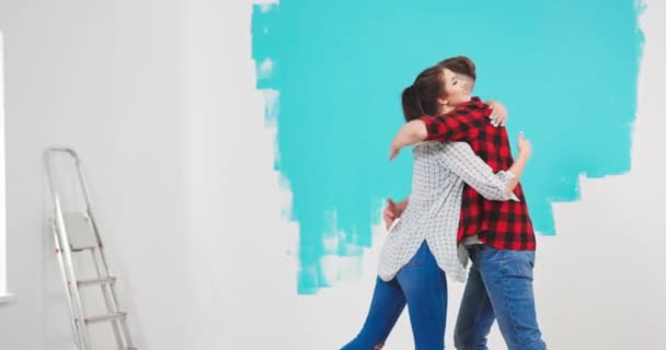 Portret radosnej młodej pary mężczyzna i kobieta przytulają się i wirują w nowym mieszkaniu, — Wideo stockowe