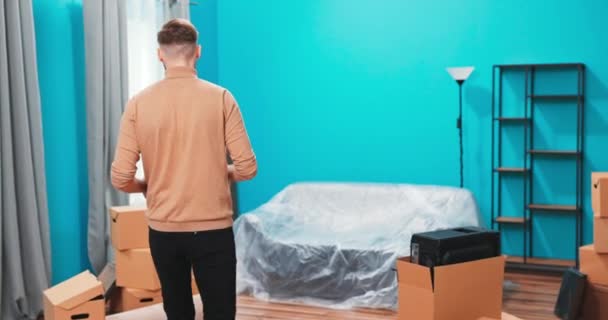 El hombre feliz se muda a la nueva primera casa traer cajas de cartón con pertenencias personales al apartamento — Vídeos de Stock