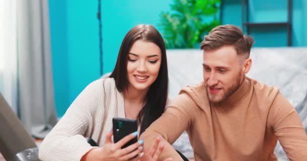 Gifta par använder smartphone välja objekt inredning för nya hus, söka renovering idéer på internet, — Stockvideo