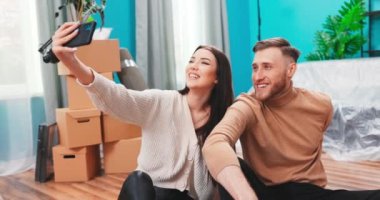 Mutlu çift, yeni evlerinde karton kutuların arasında selfie çekiyor. Yakışıklı beyaz tenli genç. 