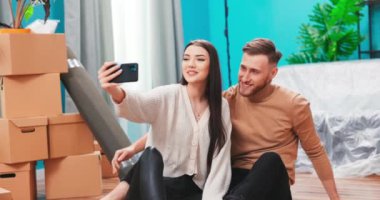 Genç mutlu Amerikan çifti karton kutuların arkasında selfie çekiyor ve yeni kanepe... 