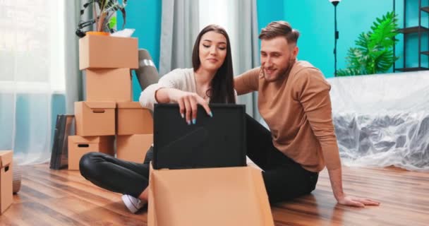 Пара переїздів в новому будинку виймають розпаковувати речі з картонних коробок тримає вигляд рамки — стокове відео