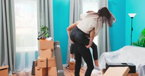 Pareja emocionada celebrando el día de mudanza, hombre levantando abrazo mujer feliz de pie entre cajas contento de — Vídeos de Stock