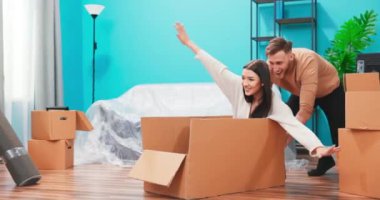 Yeni bir daireye taşınan mutlu genç çift, karton kutuda sevgilisini gezdiren erkek arkadaş, taklidini yapan kadın. 