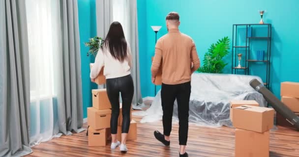 Happy married 20s couple move into new first house bring carton boxes with personal belongings — Stock Video
