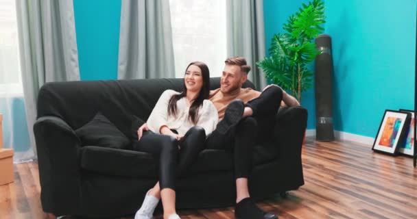 Casal europeu feliz planejamento renovação e mobiliário em casa nova, sentado em sofá confortável, animado — Vídeo de Stock