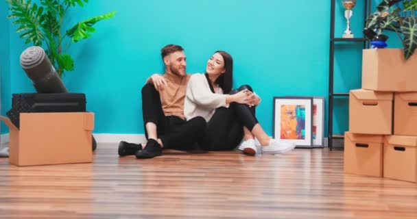Amerikanska familj par sitter på golvet i en ny lägenhet, drömmer om framtiden. — Stockvideo