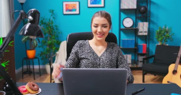 Młoda ładna brunetka dziewczyna wideo czat z przyjaciółmi podczas siedzenia przy biurku w — Wideo stockowe