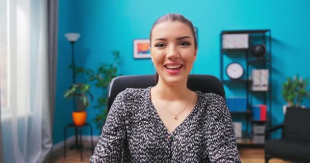 Sonriente mujer joven chats en el chat de vídeo en el ordenador portátil. Una adolescente en un casual — Vídeos de Stock