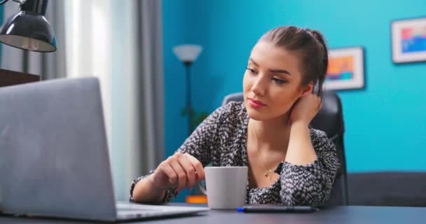 Fille est assise à un bureau dans le salon et regarde le contenu sur un ordinateur portable — Video