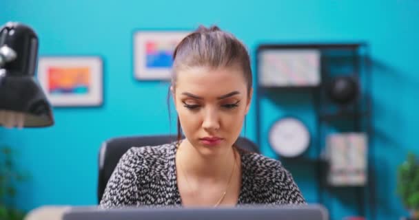 Genç bir kadın odasında dizüstü bilgisayarla ders çalışıyor. Güzel bir kadın sohbet ediyor. — Stok video