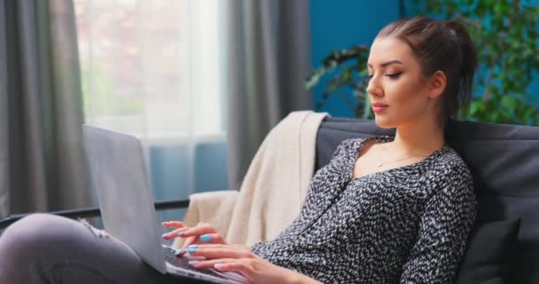 Sorrindo menina milenar sentar relaxar no sofá usando laptop moderno navegando internet sem fio ilimitada, feliz — Vídeo de Stock