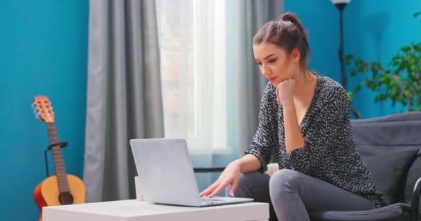 Een jonge vrouw wacht op feedback terwijl ze naar een laptopscherm kijkt. Een jong meisje. — Stockvideo