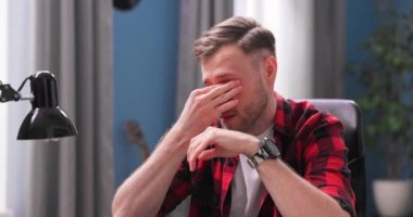 Yakışıklı bir genç adam evden uzakta çalışırken gözlerini yorgunlukla ovuşturur. A