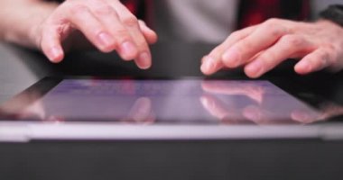 Tablet klavyeye yazı yazan ergen erkek ellerine yakın çekim. Genç bir adam daktilo ediyor.