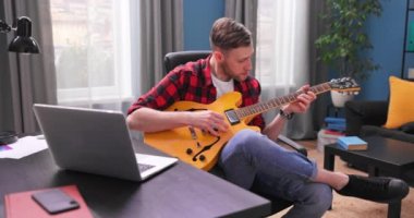 Bir erkek öğrenci elektro gitar çalmayı öğreniyor. Genç bir çocuk...