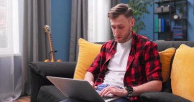 Evde dizüstü bilgisayar kullanan, ekrana bakan, sohbet eden, okuyan ya da e-posta yazan beyaz bir adam.,