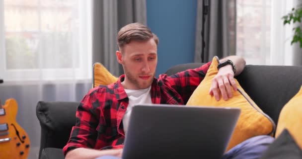 Focalizzato uomo caucasico utilizzando computer portatile a casa, guardando lo schermo, chattando, leggendo o scrivendo e-mail, — Video Stock
