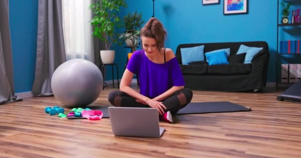 Hezká mladá žena oblečená ve fitness oblečení chatuje na video chat s osobním trenérem — Stock video