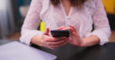 Yakın plan kız akıllı telefon kullanıyor, e-postaları kontrol ediyor. Genç ve güzel bir iş kadını uzaktan çalışıyor.