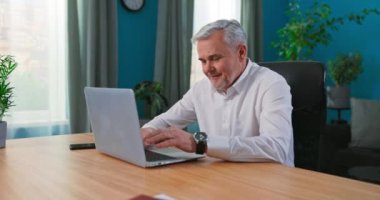 Gülümseyen mutlu orta yaşlı 50 'li yaşlarda dizüstü bilgisayar teknolojisi kullanan, sörf yapan