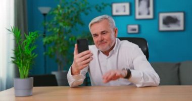 Olgun adam akıllı telefon kullanarak görüntülü konuşma yapıyor. Bağlantının tadını çıkarıyor. Dedem cep telefonuyla sohbet ediyor.