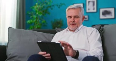 Son sınıf öğrencisi yeni dijital tablet bilgisayarını kullanmayı öğreniyor. Konsantre kıdemli adam.