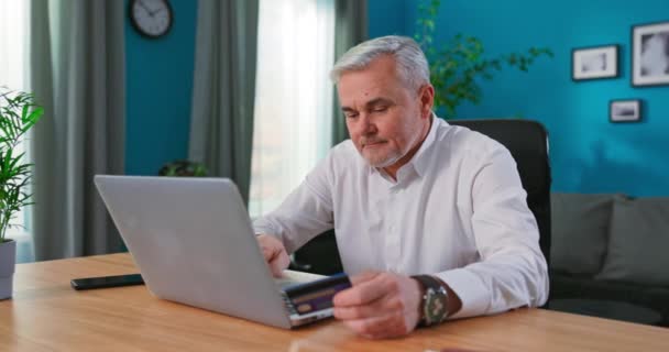 Közelkép idős férfi ülni beltéri hold hitelkártya sikeres fizetés, vásárolni az interneten, — Stock videók