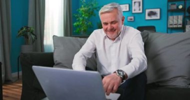 Sunny Apartmanında dizüstü bilgisayarla çalışan orta yaşlı bir iş adamı. Meşgul kıdemli yetişkin adam ödeme yapıyor.