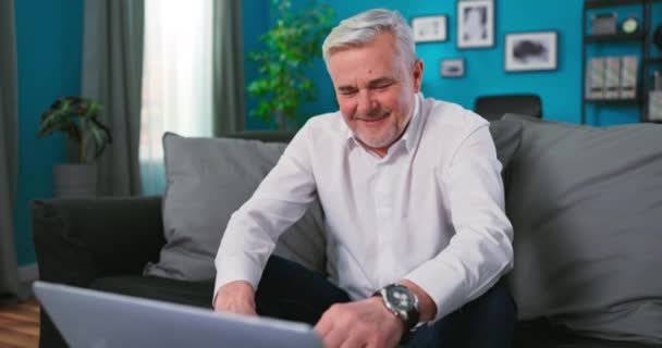 Sorrindo feliz de meia-idade de 50 anos velho homem sênior usando a tecnologia de computador portátil trabalhando on-line, navegar — Vídeo de Stock