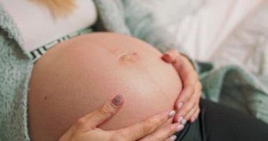 Şefkatli bir anne, aydınlık odada çıplak ve hamile bir karnını okşar. A