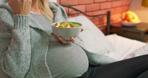 Zwangere vrouw eet fruit op bed, jonge vrouw leiden evenwichtige voeding tijdens de zwangerschap. Gezondheid van moeders — Stockvideo