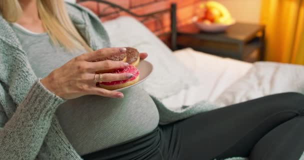 Een positieve jonge zwangere blanke vrouw is het eten van een fruitsalade en tv kijken op — Stockvideo