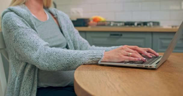 Close-up shot van de jonge zwangere moeder zitten aan de keukentafel typen iets — Stockvideo