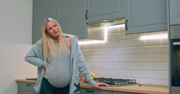 Egy terhes nő elkezdi tapasztalni a vajúdást, miközben a konyhában áll. — Stock videók