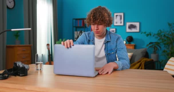 A fiatal tinédzser férfi laptoppal a hálószobájában tanul. Otthoni munka, — Stock videók