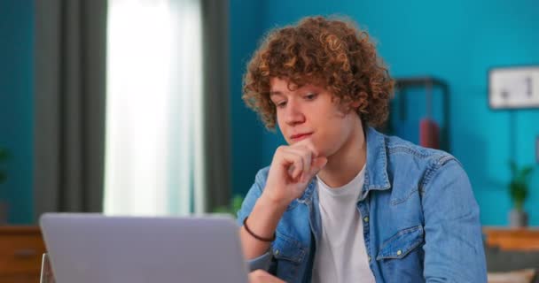 Серйозний чоловік, використовуючи ноутбук, перевіряє новини електронної пошти онлайн, сидячи на стільці, шукає друзів в — стокове відео