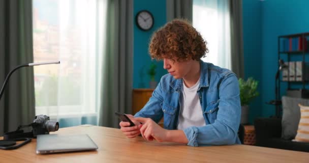 Teenage boy s chytrým telefonem, doma. Kavkazský dospívající chlap tráví čas v sociální síti — Stock video