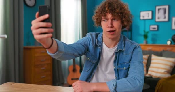 Tonåring manlig användning smartphone skivor video för sociala nätverk gör roliga ansikten, flörtar skrattar ser — Stockvideo