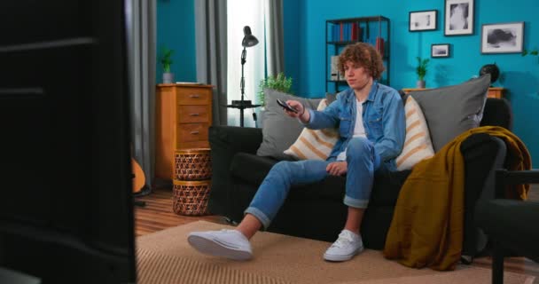 Adolescent garçon assis sur confortable canapé et regarder comédie à la télévision rire avec humour blagues — Video