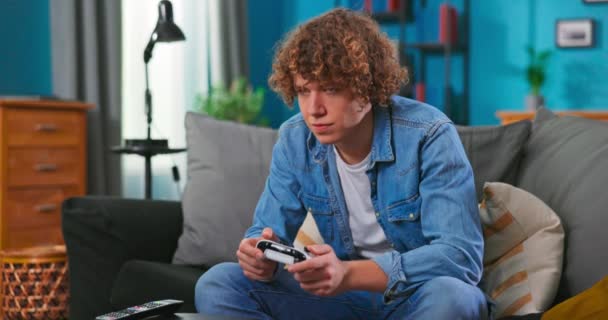 Счастливый мужчина играет в видеоигры в квартире - веселый мальчик-подросток развлекается с новым — стоковое видео