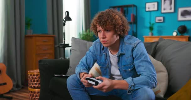 Мальчик-подросток наслаждается видеоигрой, используя контроллер, сконцентрированный на интересной деятельности в квартире. Подростки — стоковое видео