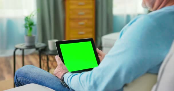 Dorosły starzec w domu ogląda zielony ekran makiety Tablet. Siedzi na stole. — Wideo stockowe