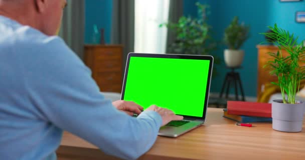 Detailní záběr muže používá notebook se zeleným displejem při sezení na stole — Stock video