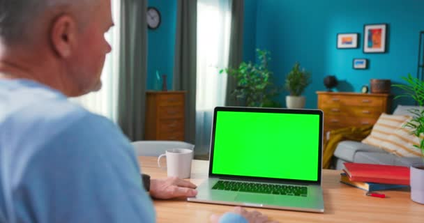 Κοντινό πλάνο ενός ανθρώπου χρησιμοποιεί φορητό υπολογιστή με πράσινη οθόνη Mock-up, ενώ κάθεται στο γραφείο — Αρχείο Βίντεο