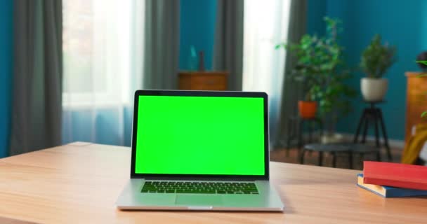 Ноутбук с зеленым макетом экрана на столе в уютной гостиной на — стоковое видео