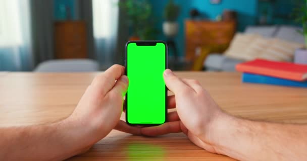 Primer plano del hombre usando Green Mock-up Screen Smartphone en modo retrato mientras está sentado en su — Vídeos de Stock